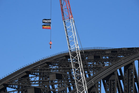 CFMEU flags fly from a crane near the Sydney Harbour Bridge on Tuesday.