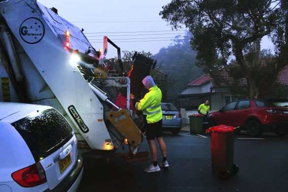 Men load rubbish into a truck that collects residential waste along Macauley street in Leichhardt.