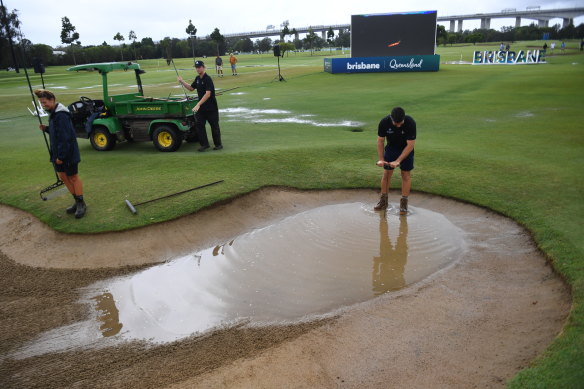 Workers drain a bunker as play is suspended during the Australian PGA at Royal Queensland Golf Club in Brisbane.