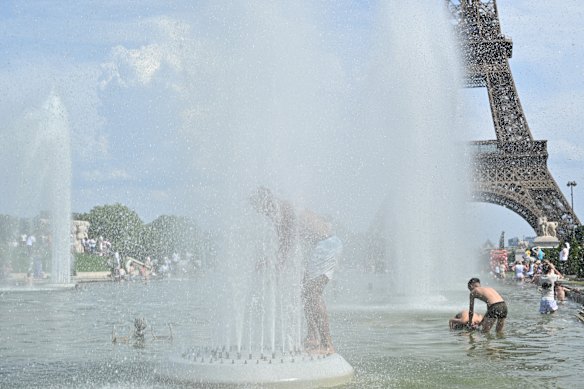 La gente si rinfresca nelle fontane dei giardini del Trocadero, con la Torre Eiffel sullo sfondo, a Parigi.