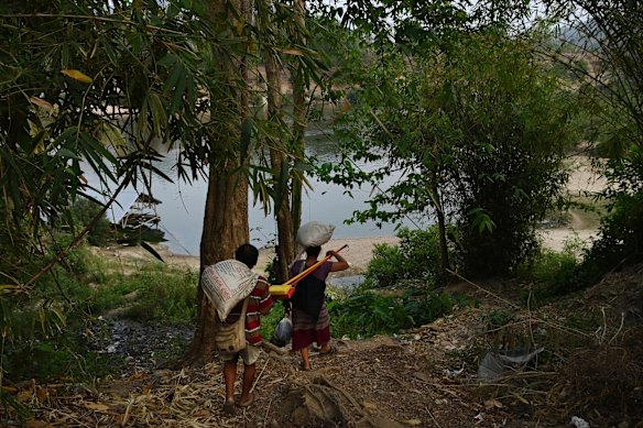 Carrying supplies, a couple from Myanmar walk along a track towards the Moei River border and home. 