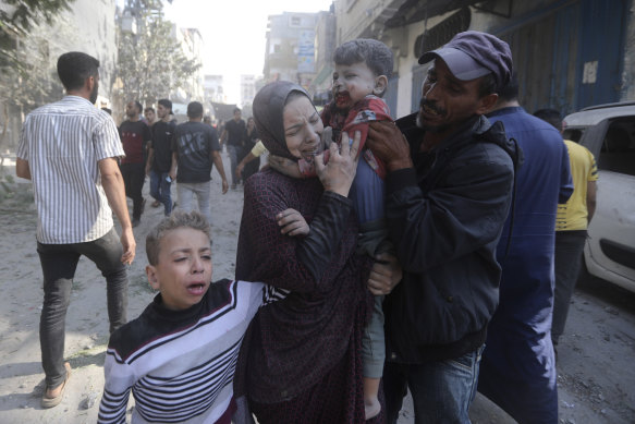 A Palestinian woman cries as she carries her wounded son following an Israeli airstrike.