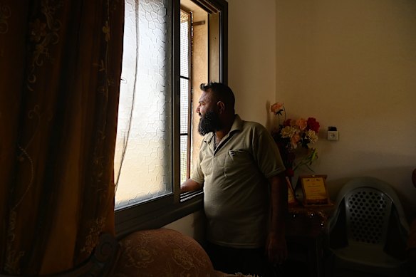 Ayman Soufan looks out at a settler outpost from his home in Burin. He and his brother take it in turns to watch for settler attacks. 