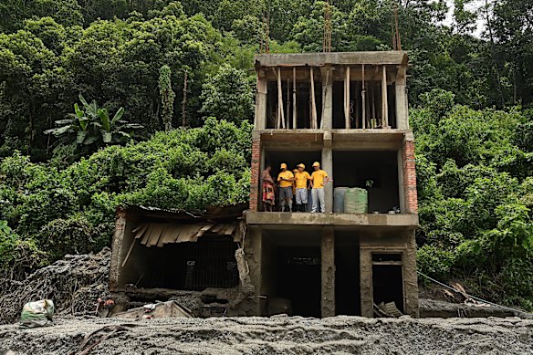 Search and rescue volunteers talk to a resident amid the wreckage of a building in Dhunge, Nepal. 