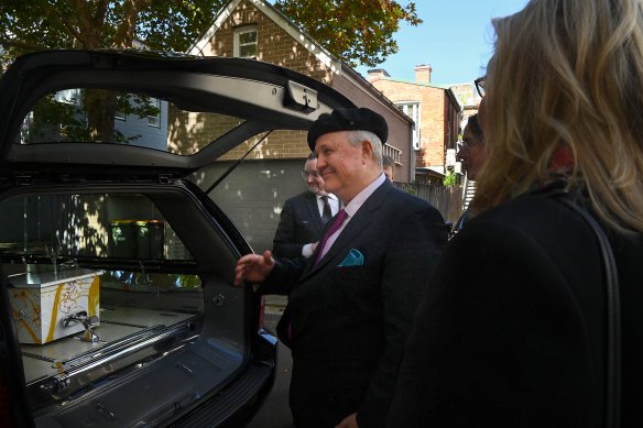 Tim Olsen (left) wears his father John Olsen’s beret before returning it on top of his coffin in Paddington on Thursday.