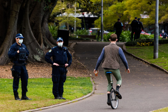 A man rides a unicycle past police in the CBD exclusion zone on Saturday.