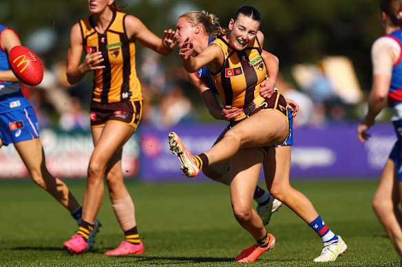 Aine McDonagh of the Hawks kicks for goal while being tackled.