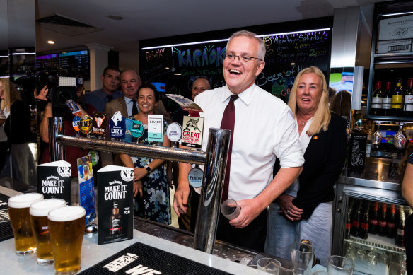 Scott Morrison pulls a beer and meets the patrons at the Cazalys Palmerston Club near Darwin on Anzac Day.