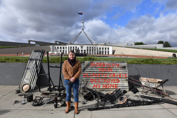 Melinda Plesman stands with the remains of her burn't out house outside Parliament House on Monday.