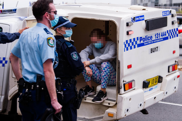 A woman in activewear sits in the back of a police vehicle in Sydney.