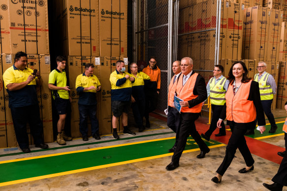 Prime Minister Scott Morrison walks past workers at the Rheem hot water system factory on Tuesday.