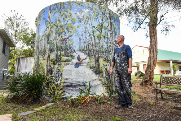 Artist Simon White with one of his murals, on a water tank, in Loch Sport.