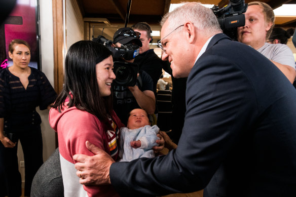 Prime Minister Scott Morrison greets Lisha Luo and her month-old baby Muxi at the Syndal Baptist Church in Melbourne.