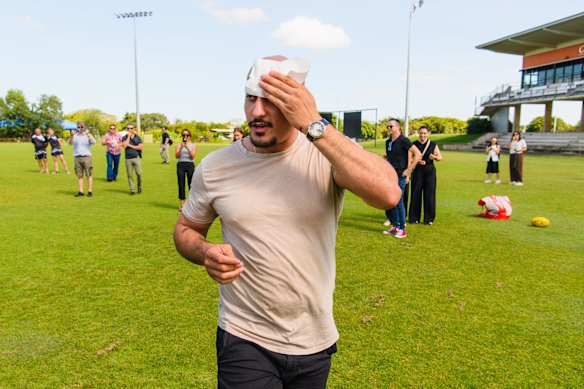 Cameraman Ghaith Nadir clutches his head after he was injured by a wayward footy kick from Peter Dutton.