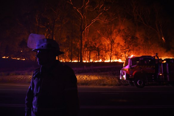 An RFS firefighter with the Charmhaven unit monitors a small flare-up on New Year's Day on the Kings Highway near Batemans Bay.