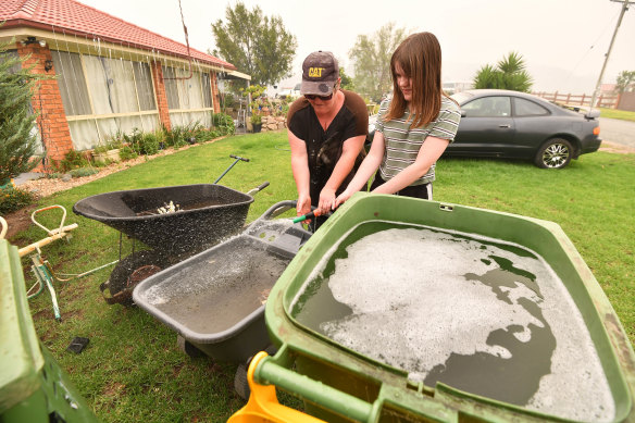 Clare  Morgan and her daughter Abbey  fill up bins and barrows with water to defend their home.