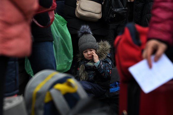 A crying child sits among luggage at Lviv railway station as Ukrainians flee the country.
