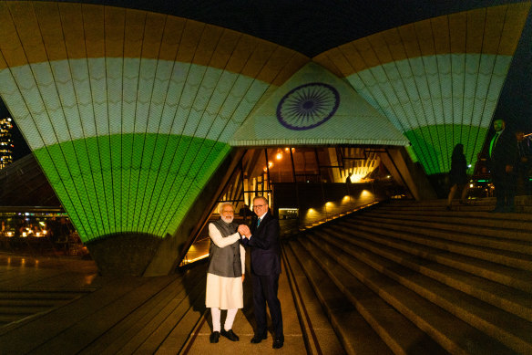 Narendra Modi and Anthony Albanese pose in front of the sails of the Opera House bearing the colours of the Indian flag.