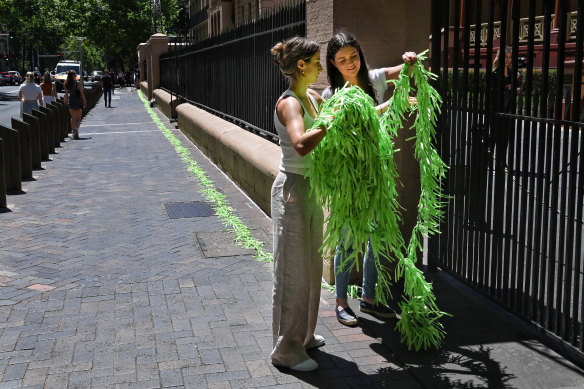 Chloe Korbel, 17, and Lucinda Hoffman, 26, string a line of 6000 ribbons outside NSW Parliament: one representing each young person who submitted a sexual assault testimony to Chanel Contos’ petition.