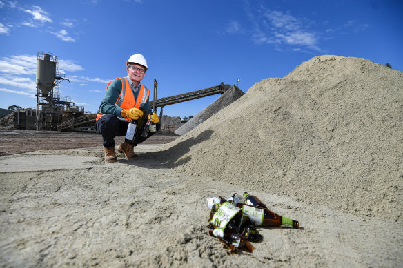 The firm's general manager recycling industries Mark Barraclough with glass bottles before and after being processed in a pile of sand.  