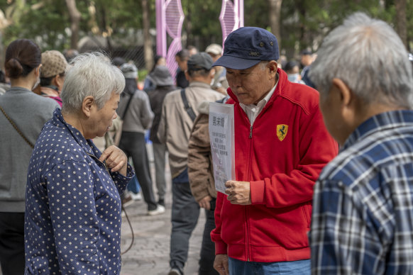 A woman tries to figure out information on a paper post held by a man at the marriage market in Shanghai. 