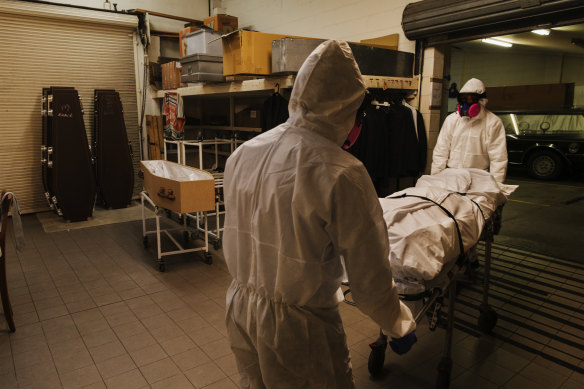 Funeral workers transfer the body of a man who died in the past week of COVID-19 into a funeral home. 