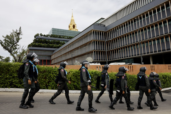 Police officers in riot gear walk past Parliament House in Bangkok