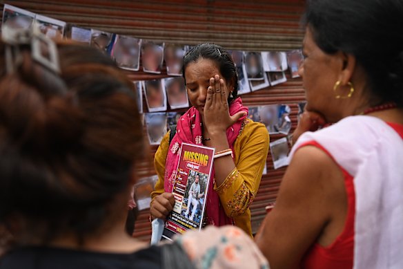 Champa Kumari Marchaha holds a photo of her husband, Basanta Tharu, on Friday. Behind are her images of some of the bodies being processed in Kathmandu.