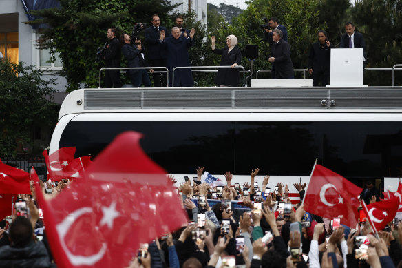 Turkish President Recep Tayyip Erdogan and his wife Emine Erdogan gesture to supporters as he claims victory in the presidential election run-off outside his residence.