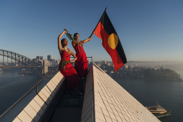 Abigail Delaney and Dubs Yunupingu from the Jannawi Dance Clan, from the Darug nation, flying the Aboriginal flag on top of the Opera House to promote Dance Rites, a celebration of First Nations dance.