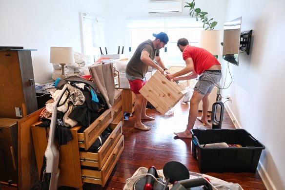 Lachlan Mackay (left) removes water-damaged items from his home. 