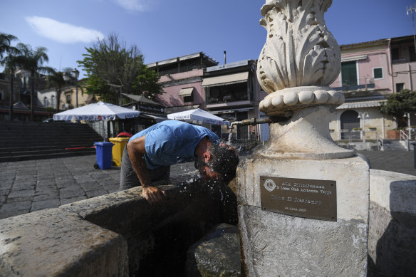 A man attempts to cool himself down at a fountain in Aci Trezza, Sicily, where temperatures hit a new European record.