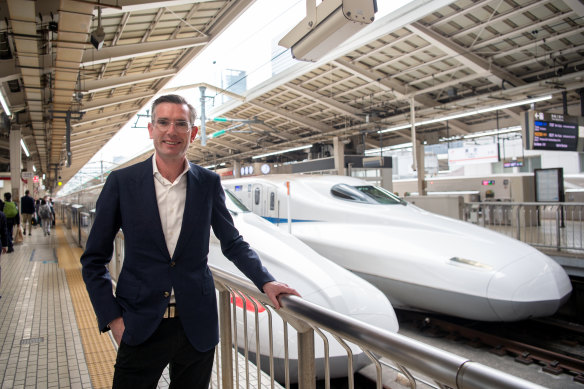 Premier Dominic Perrottet poses alongside a Shinkansen bullet train at Tokyo Train Station.