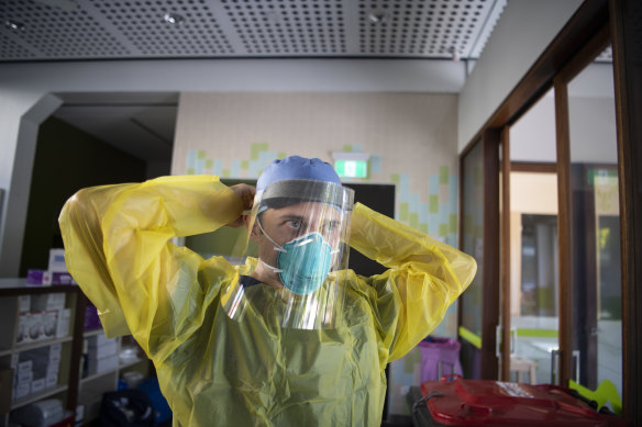 Nurse Jarrod Tunks applies his face shield before starting his shift.