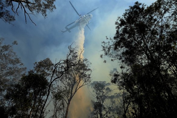 A helicopter dumps water on a bushfire that NSW Rural Fire Service are controlling from a property on Silverdale Road in Wallacia.