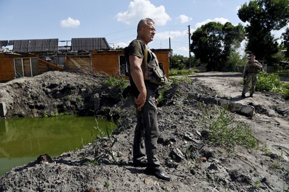 Barvinkove mayor Oleksandr Balo next to a crater from a Russian missile that destroyed and damaged nearby buildings. 