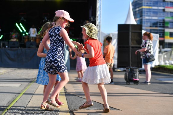 Clara Potter, left, and Thea Razentals, right, celebrate at an open-air dance floor in Melbourne’s Docklands. 