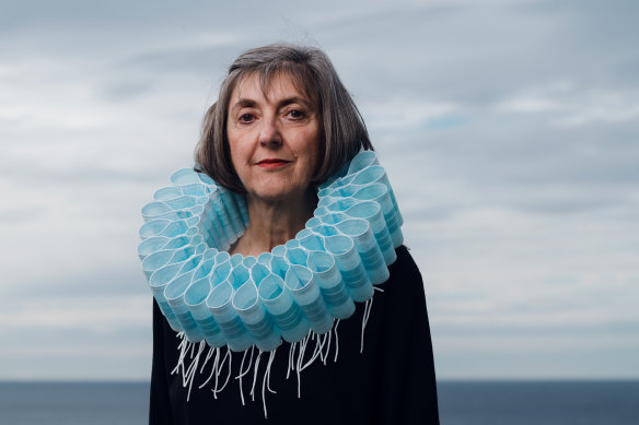 Sydney artist and designer Ruth Downes wears a collar of masks that she made to illustrate the impact on the environment of single-use items.  