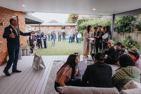 Auctioneer Jason Keen in matching tie and gavel keeps up the pace as the sales team consults buyers at the auction of 5 Malvern Avenue, Roseville.