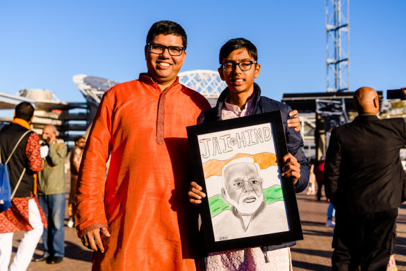 Saurabh Mishra and his son Aarav from Schofields with a drawing of Modi  outside the Qudos Bank Arena on Tuesday. 