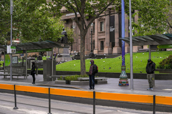 Passengers socially distance while waiting for a tram on Swanston Street on Monday. 