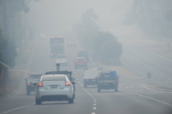Cars drive through smoke haze along Forest Way, Belrose, on Friday.