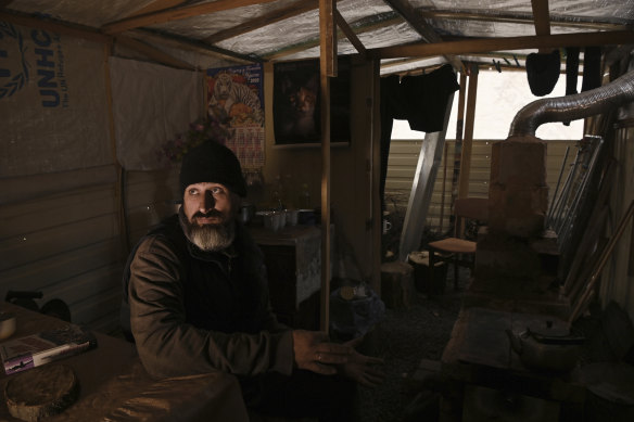 Serhiy, 46, sits in the outdoor kitchen with a wood stove where his family and neighbours can keep warm.