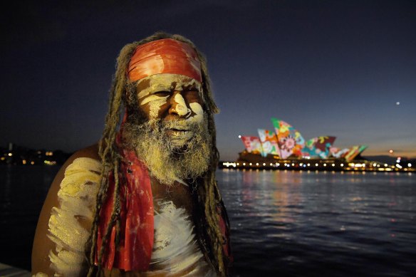Koomurri performer Les Daniels in front of a projection of artwork by Pitjanjara artist David Miller on the sails of the Opera House on Australia Day.