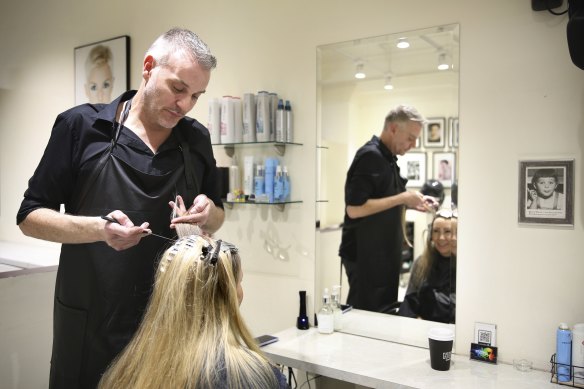 Russell James attends to the locks of a client in his Sydney CBD salon.