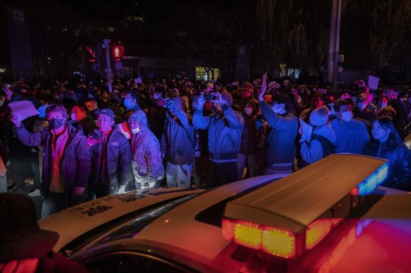 Protesters march by a police in Beijing. 