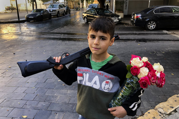 A displaced Syrian boy, Omar, 10, holds a toy gun while selling flowers on the street in Beirut, Lebanon.