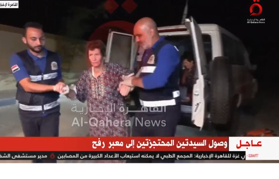 Red Cross workers help Yocheved Lifshitz, 85, to a waiting ambulance at the Rafah border crossing after she was released by Hamas militants.