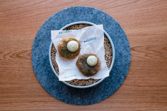 Potato scallop with seaweed, vinegar, served on scrunch of paper on a bowl of grains. 