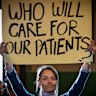 An attendee holds a placard during an emergency public meeting at Fitzroy Town Hall last year about the cohealth closures.